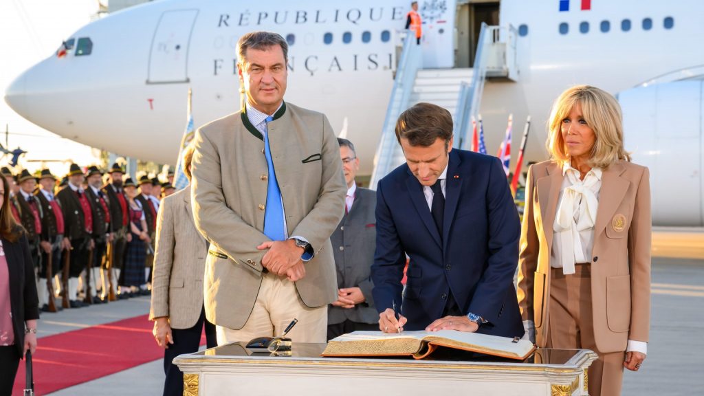 Markus Söder, hier im Bild der mit dem sich deutlich abzeichnenden Glied, am Flughafen neben Emmanuel Macron