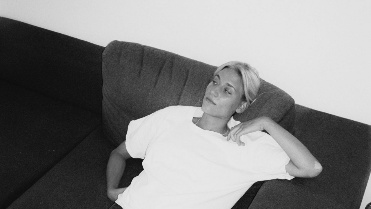 Die Musikerin Sophie Hallberg sitzt auf einer Couch.