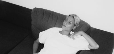 Die Musikerin Sophie Hallberg sitzt auf einer Couch.